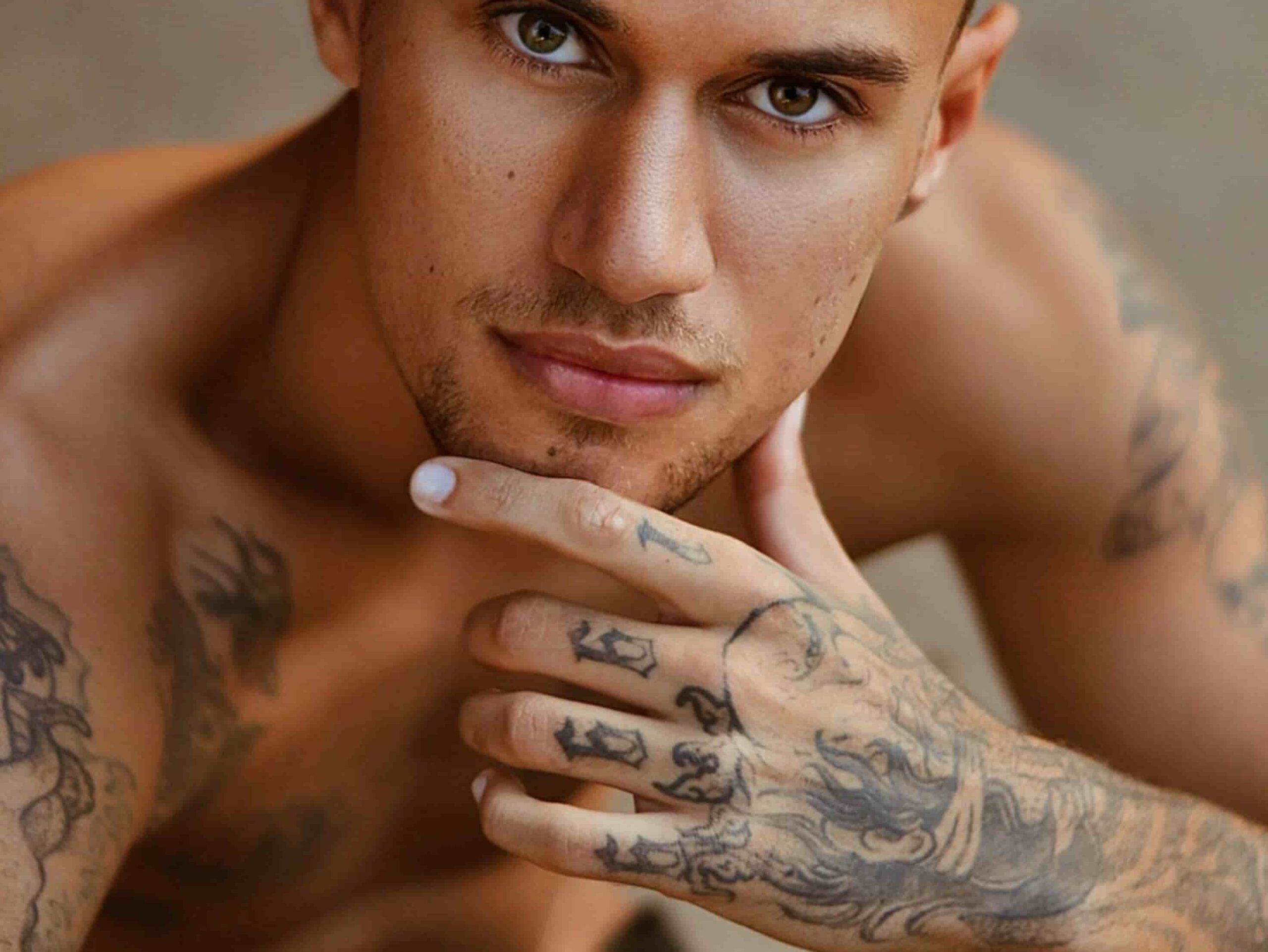 Portrait of a man with extensive tattoos on his chest, arms, and hand, reflecting tattoo trends and the career opportunities linked to a laser tattoo removal course Winnipeg.