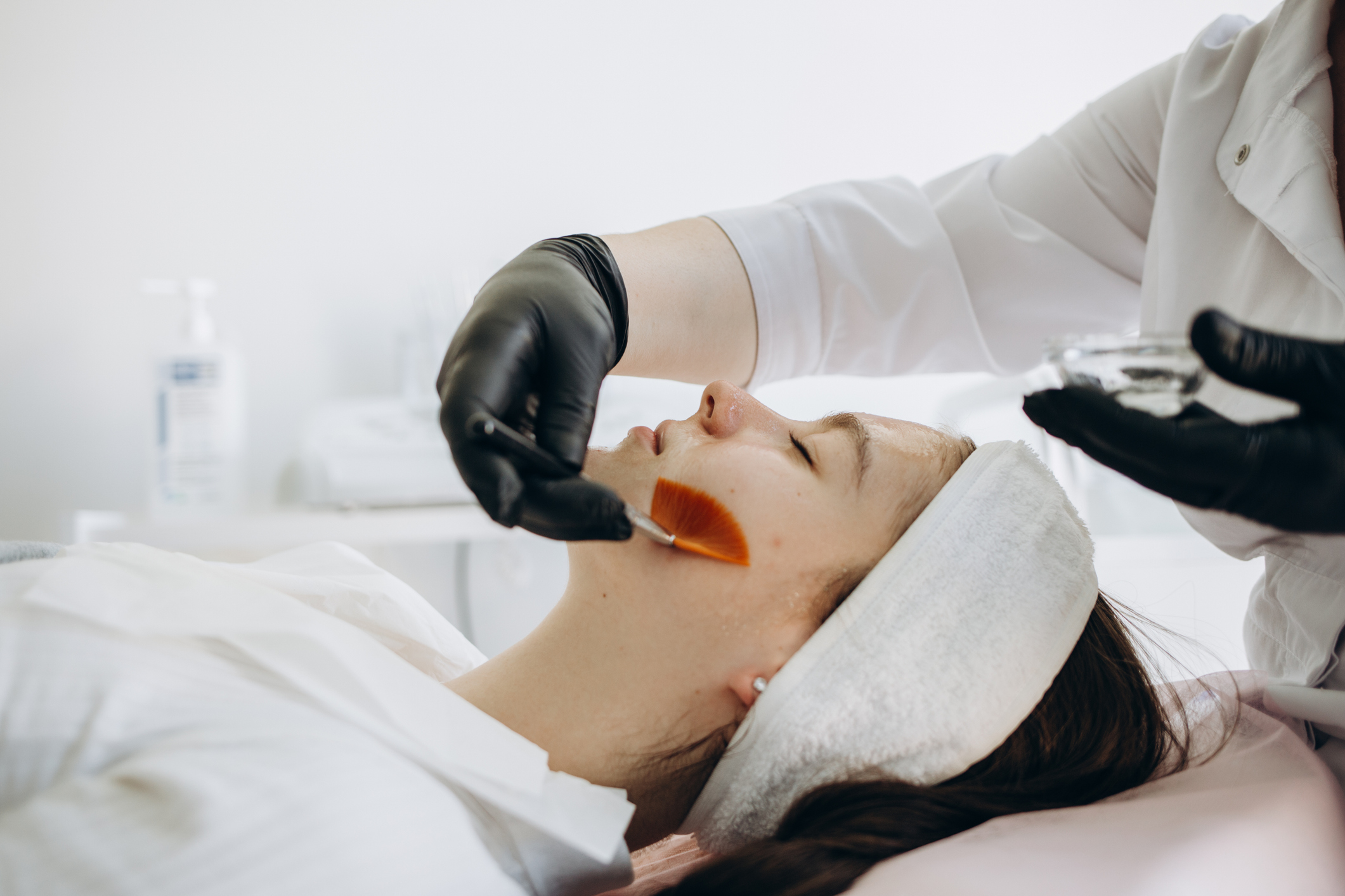 Esthetics student performing a facial under instructor supervision